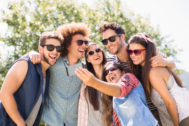 Amici felici nel parco prendendo selfie