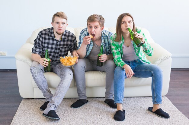 Amici felici o tifosi di calcio che guardano il calcio in tv e celebrano la vittoria a casa. Concetto di amicizia, sport e intrattenimento.