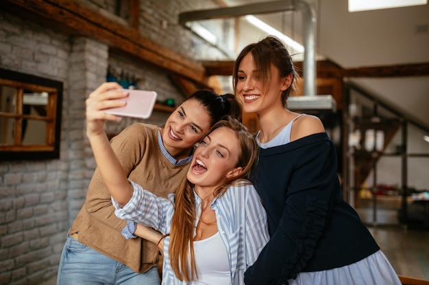 Amici femminili allegri che prendono selfie