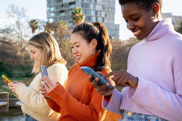 Amici femminili allegri che usano i telefoni cellulari Concetto di comunità millenaria dipendente dalla tecnologia