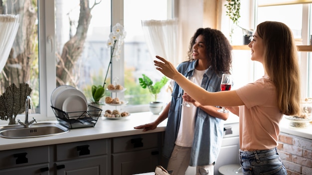 Amici femminili che socializzano in cucina davanti al vino