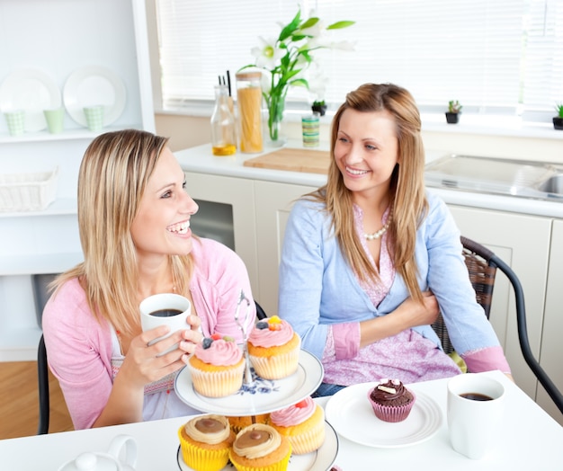 Amici femminili con torte e caffè parlando insieme in cucina