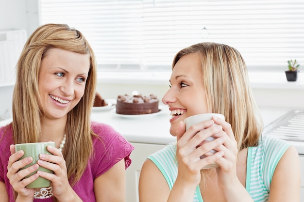 Amici femminili contentissimi che tengono una tazza di caffè a casa