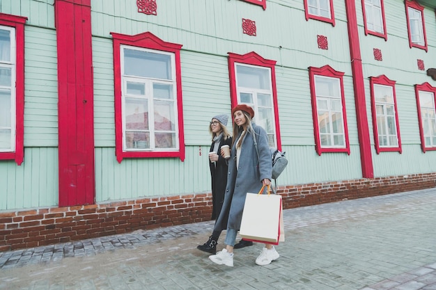 Amici femminili felici che comperano due belle giovani donne che si divertono a fare shopping in città con le borse della spesa