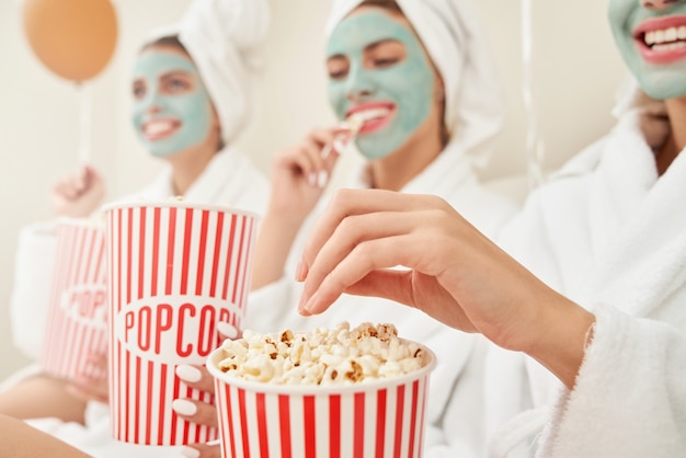 Amici femminili in accappatoi che mangiano popcorn.