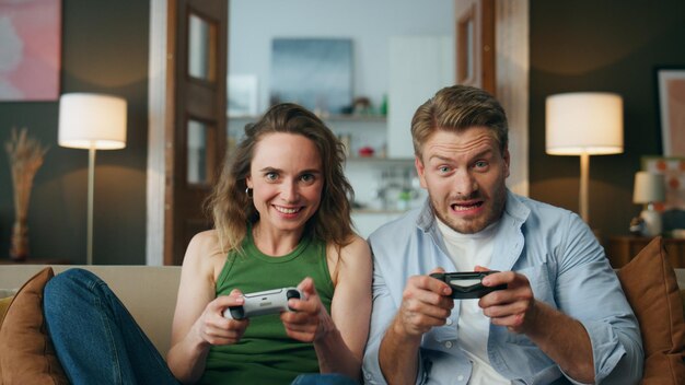 Amici gioiosi si godono l'attività di videogiochi a casa coppia spensierata che tiene in mano i gamepad