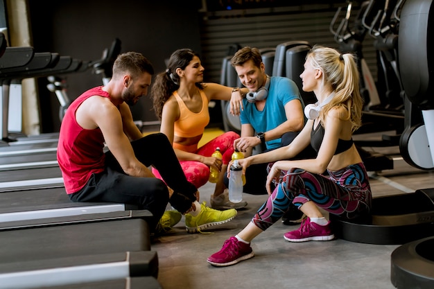 Amici in abiti sportivi parlando e ridendo insieme mentre riposa in palestra dopo un allenamento