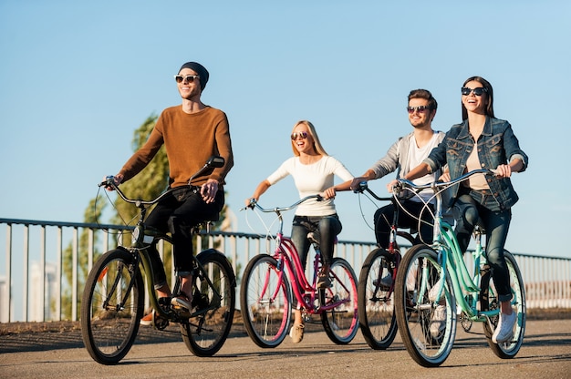 Amici in bicicletta. Integrale di quattro giovani che vanno in bicicletta e sorridono