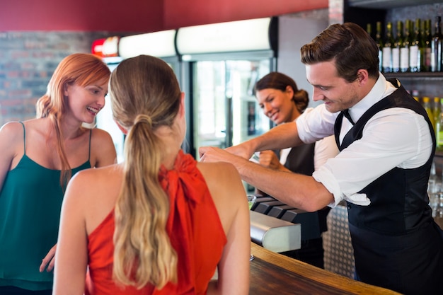 Amici in piedi al bancone mentre il barista prepara un drink