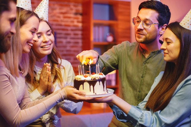 Amici in piedi insieme tenendo un piatto con una torta e festeggiando il compleanno