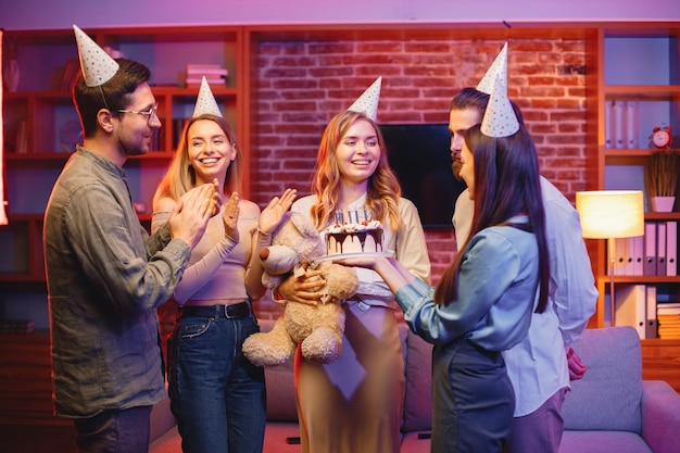 Amici in piedi insieme tenendo un piatto con una torta e festeggiando il compleanno