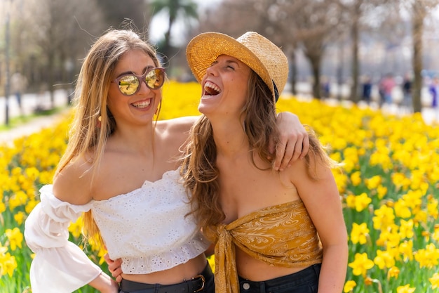 Amici in vacanza in città accanto a dei bei fiori gialli che sorridono molto e si godono la primavera