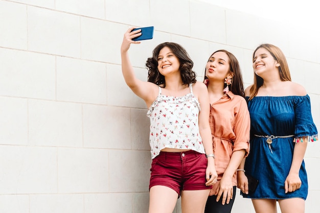 Amici latinoamericani allegri che prendono una foto del selfie all'aperto.