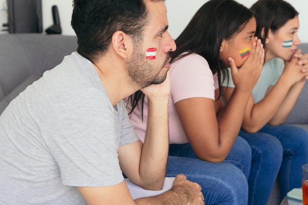 Amici latinoamericani guardano i Mondiali sul divano di casa. Sono arrabbiati perché la squadra sta perdendo brutte emozioni