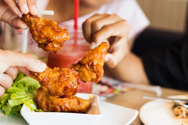 amici, mani della gente che mangiano pollo fritto squisito