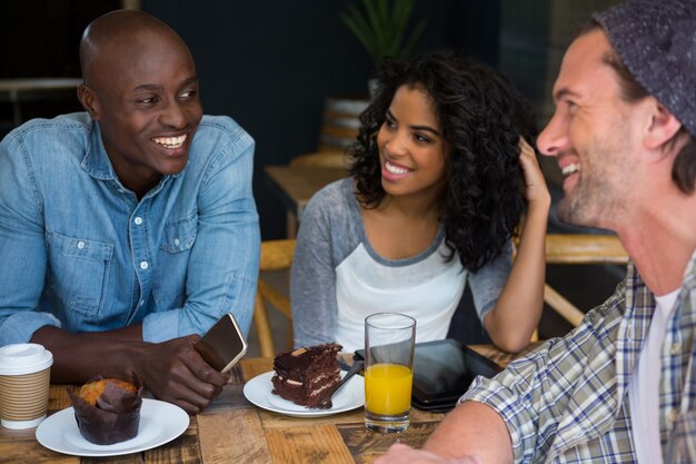 Amici maschii e femminili che parlano al tavolo in caffè