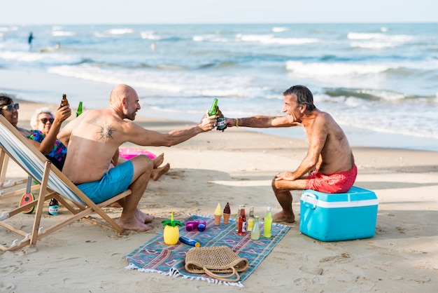 Amici maturi con birre in spiaggia