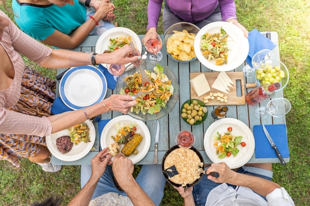 Amici multiculturali seduti al tavolo di legno amici che cenano hanno piatti pieni di cibo