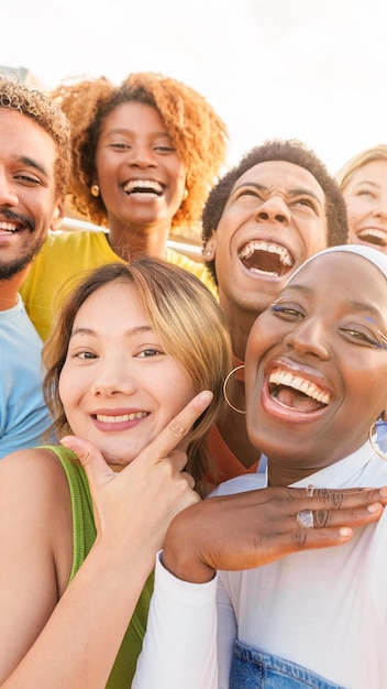 Amici multietnici eccitati che si fanno un selfie all'aperto durante il tramonto