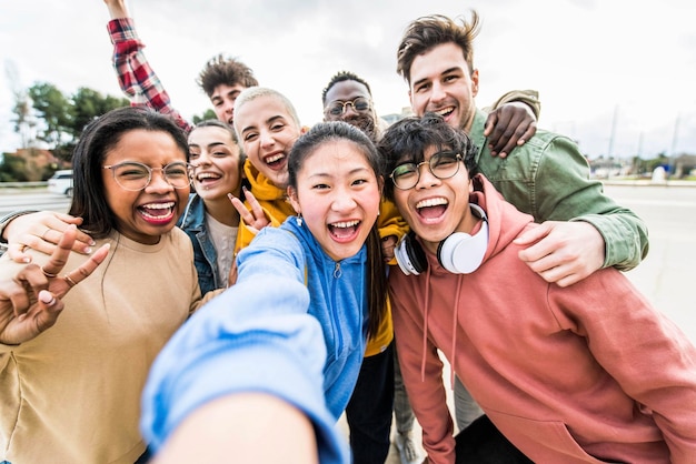 Amici multirazziali che scattano selfie di gruppo di grandi dimensioni sorridendo alla telecamera