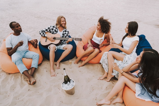 Amici multirazziali che suonano musica al Beach Party