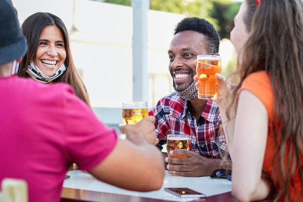 Amici multirazziali che tifano con birra e sorridono