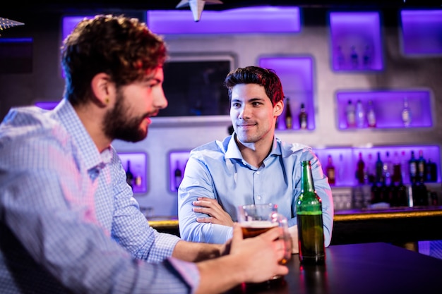 Amici seduti al bancone del bar e la birra