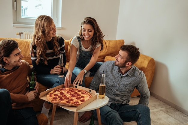 Amici seduti in soggiorno a mangiare la pizza