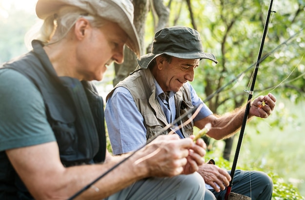 Amici senior che pescano in riva al lago