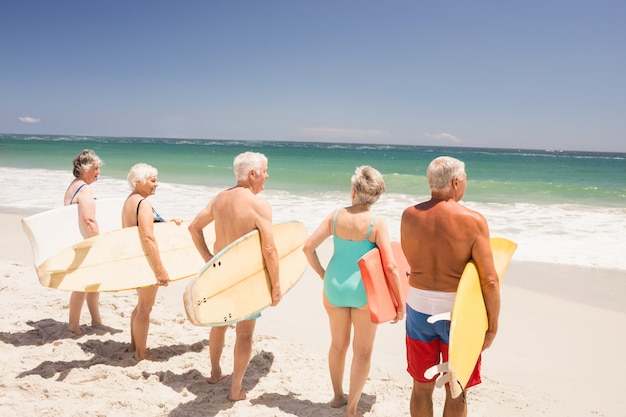 Amici senior che tengono tavola da surf