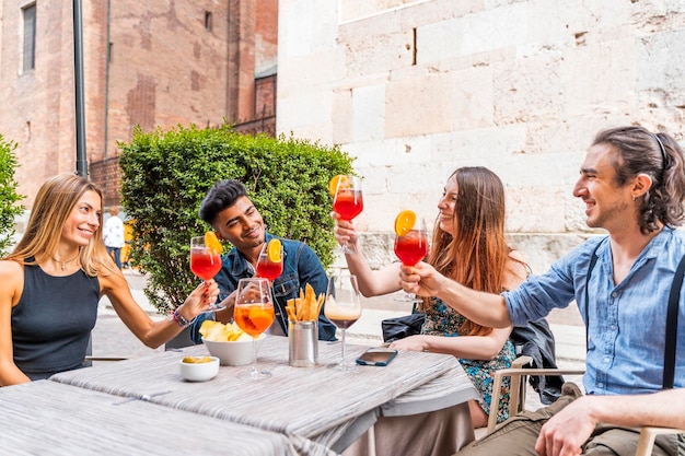 Amici sorridenti che brindano alle bevande mentre sono seduti al caffè