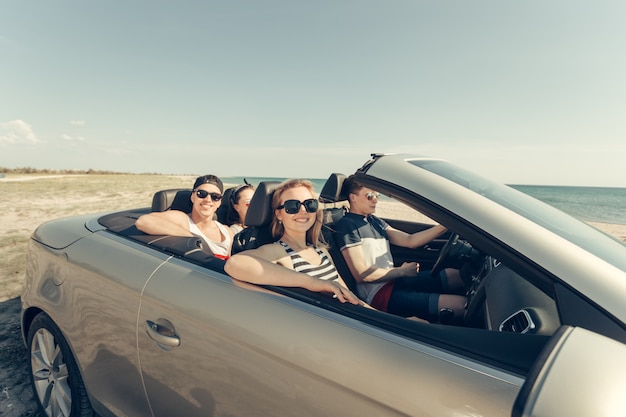 Amici sorridenti che guidano auto vicino al mare e divertirsi