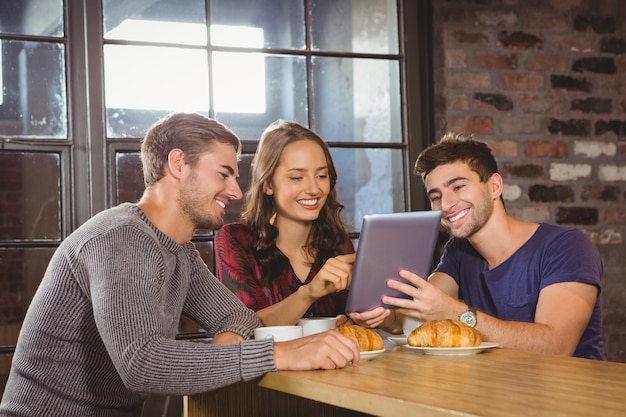 Amici sorridenti che per mezzo insieme del computer della compressa