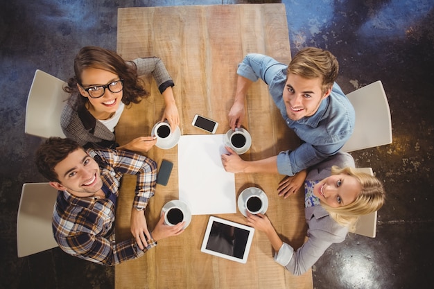 Amici sorridenti che si siedono e che bevono caffè