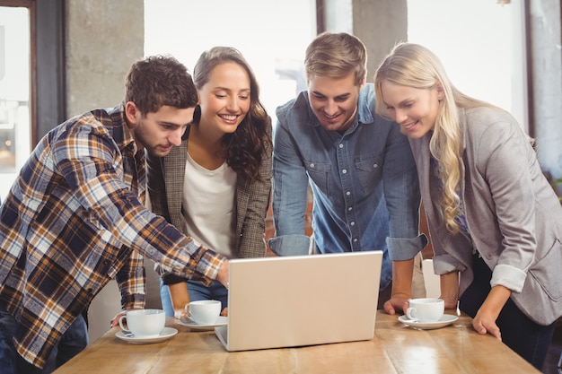 Amici sorridenti che stanno e che indicano sullo schermo del computer portatile