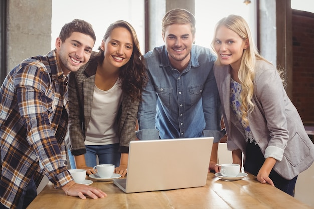 Amici sorridenti che stanno intorno al computer portatile