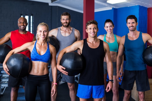 amici sorridenti che tengono la palla di esercizio in palestra