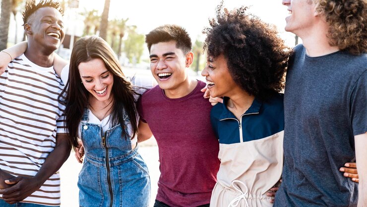 Amici sorridenti multirazziali che si divertono a camminare sulla strada della città