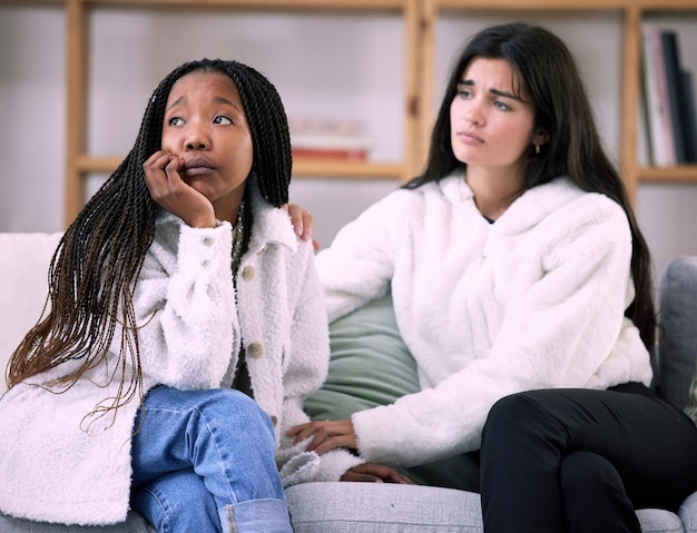 Amici tristi e preoccupazione con le donne sul divano nel soggiorno per conforto dolore e depressione Salute mentale supporto emotivo e cura con la ragazza che consola a casa per consigli di solidarietà e simpatia