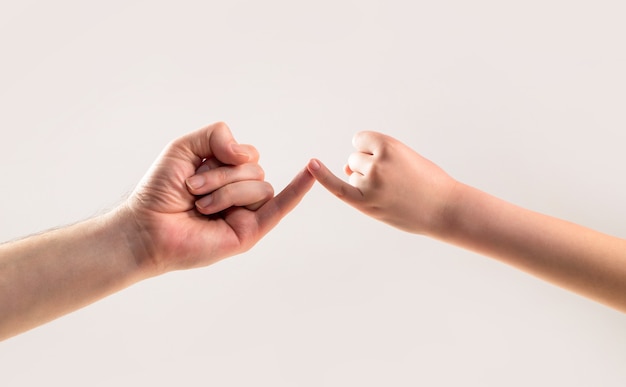 Amicizia di generazioni. Padre, figlia che fa il concetto di amicizia di promessa. Bambino gancio mignolo insieme. Il mignolo delle due mani si tiene insieme. Mostra amicizia e perdono.