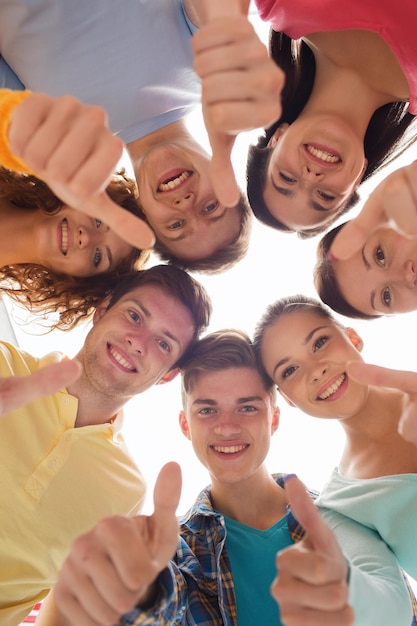 amicizia, gioventù, gesto e persone - gruppo di adolescenti sorridenti in cerchio che mostra i pollici in su