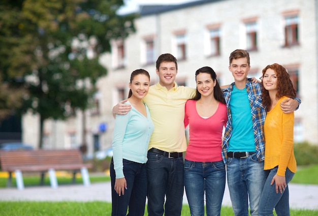 amicizia, istruzione, vacanze estive e concetto di persone - gruppo di adolescenti sorridenti in piedi e abbracciati sullo sfondo del campus