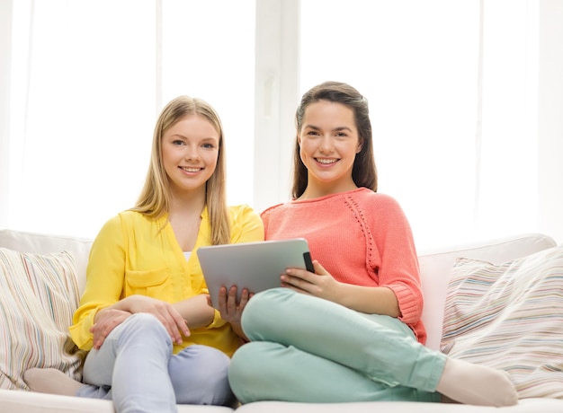 amicizia, tecnologia e concetto di internet - due ragazze adolescenti sorridenti con computer tablet pc a casa