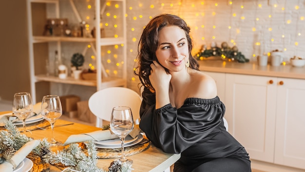 Amico di due belle ragazze felici allegre che ride al tavolo da pranzo di Natale sullo sfondo della cucina di Capodanno