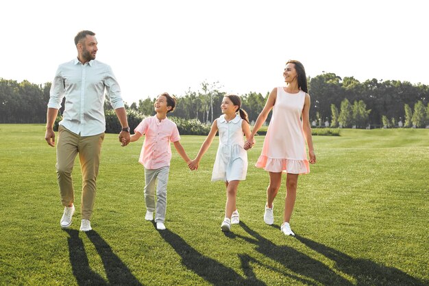 Amo la mia famiglia per tutta la lunghezza della famiglia felice e giovane di quattro persone che si tengono per mano