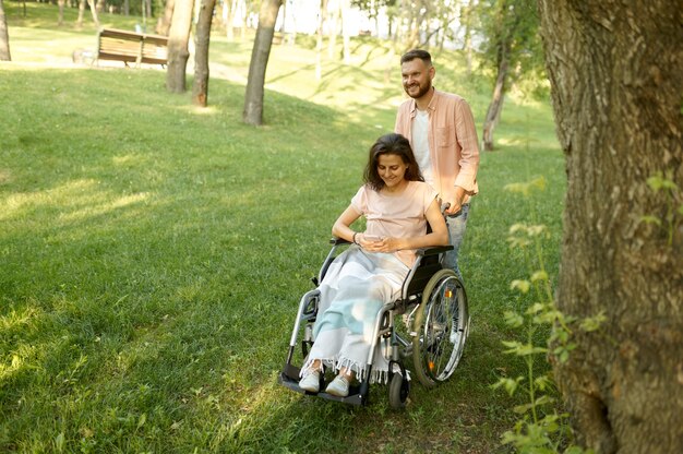 Amore coppia con sedia a rotelle che cammina nel parco autunnale