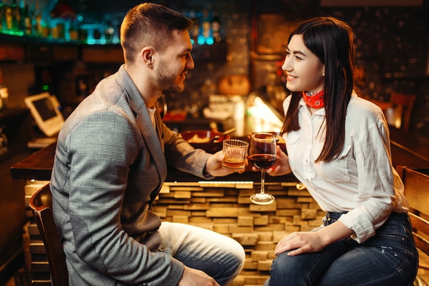 Amore coppia rilassante con alcool al bancone del bar in legno, serata romantica.