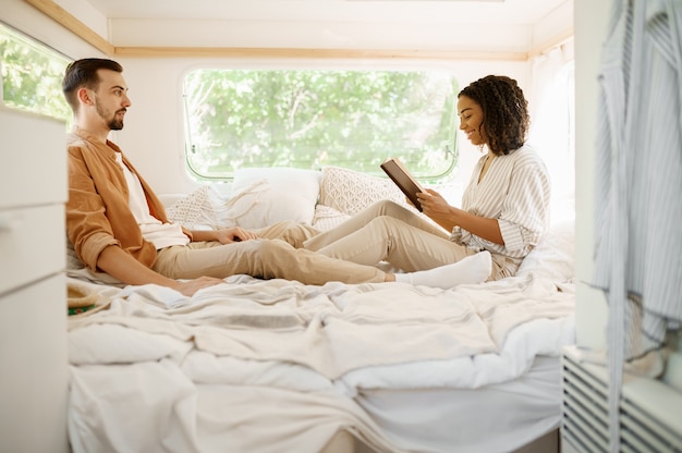 Amore coppia rilassarsi in camera da letto, campeggio in una roulotte. Uomo e donna viaggiano in furgone, vacanze in camper, svaghi campeggiatori in camper