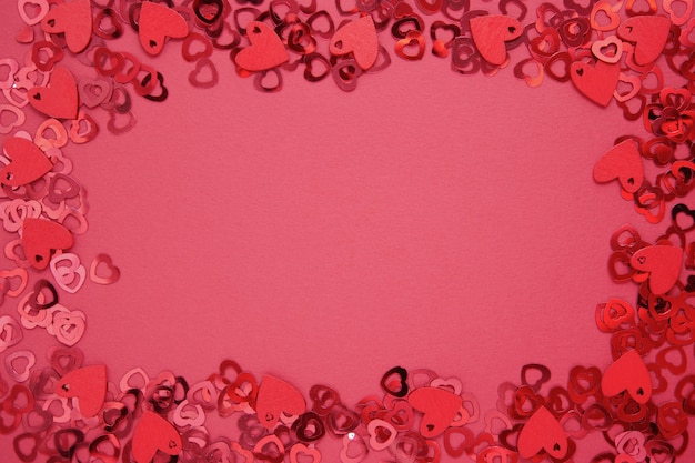 Amore cornice astratta, bordo, sfondo rosso con glitter a forma di cuore. San Valentino piatto disteso.