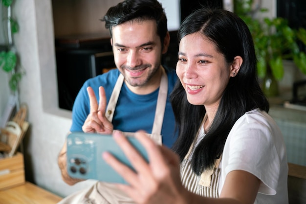 Amore e coppia romantica fidanzato e fidanzata selfie foto con il telefono cellulare insieme durante la cena cucinare per la celebrazione di san valentino in cucina